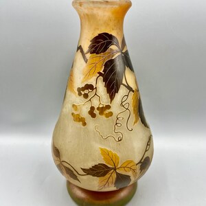 May include: A tall, clear glass vase with a pearlescent finish and a floral design. The vase features a pattern of brown and gold leaves and vines with small, gold berries.