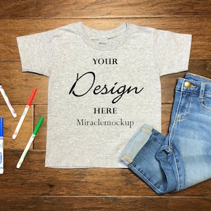 Kids Sport Grey Gildan Mock up Toddler T-Shirt Toddler Jeans Markers Wood Background Flat Lay Mockup Template mc4