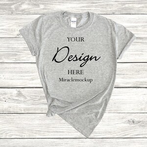 K&ouml;nnte beinhalten: Ein graues T-Shirt mit dem Text "YOUR Design HERE Miraclemockup" auf der Vorderseite.