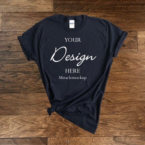 Puede incluir: Una camiseta azul oscuro con el texto "YOUR Design HERE Miraclemockup" impreso en la parte delantera.