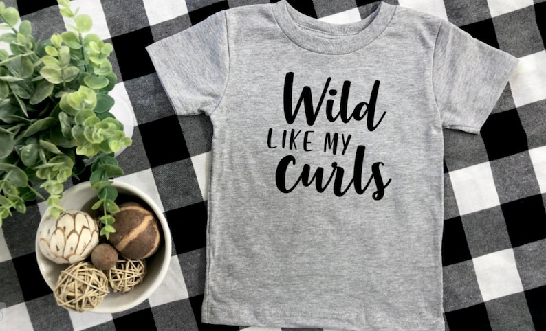 May include: Gray short-sleeved t-shirt with black text that reads "Wild Like My Curls".
