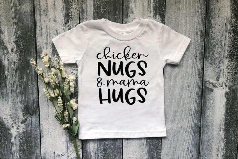 May include: White baby t-shirt with black text that reads "chicken NUGS & mama HUGS".