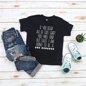 May include: Black t-shirt with white text that reads "If you read all of this shirt you will find out that I am going to be a big brother".