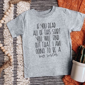 Puede incluir: Camiseta gris de manga corta con texto negro que dice "Si lees toda esta camiseta, descubrir&aacute;s que voy a ser una hermana mayor."