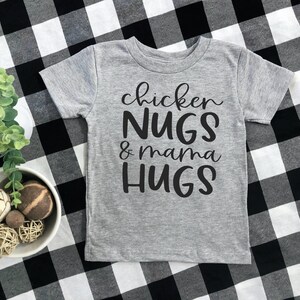 May include: A gray short-sleeved t-shirt with black text that reads "chicken NUGS & mama HUGS".