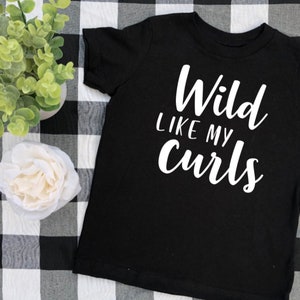 May include: Black t-shirt with white text that reads "Wild like my curls".