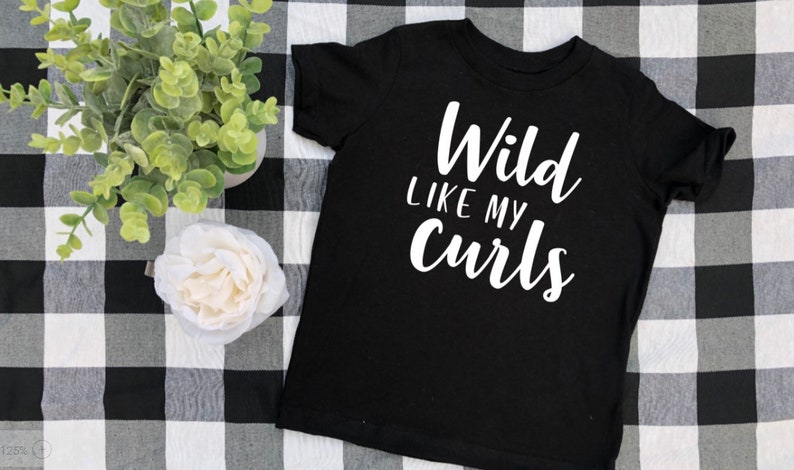 May include: Black t-shirt with white text that reads "Wild like my curls".