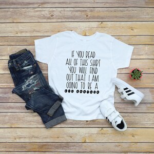 May include: White t-shirt with black text that reads "If you read all of this shirt you will find out that I am going to be a big brother."