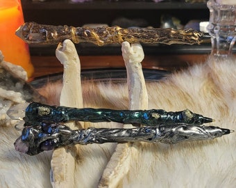 May include: Three decorative pens with crystal tips. The pens are made of different materials, including wood, metal, and resin. The pens are displayed on a white stand.