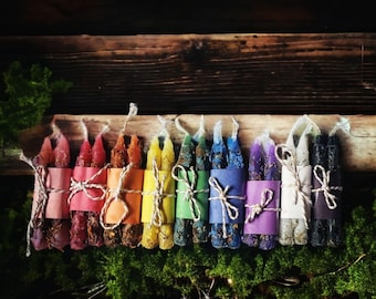 May include: A set of 20 colorful candles, tied together with twine, arranged in a rainbow pattern. The candles are wrapped in paper and are ready to be used for rituals or spell work.