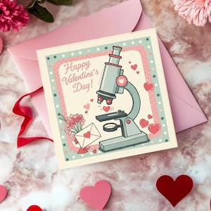 Op de afbeelding: Valentijnsdagkaart met een microscoopillustratie, omringd door roze harten en een roze envelop. De kaart zegt "Happy Valentine's Day!" in een speels lettertype, met een bloemenboeket en een envelop met een hart.