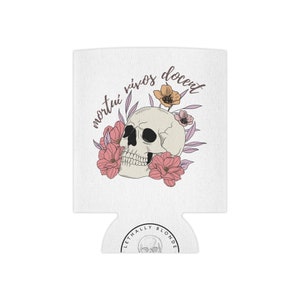 May include: White can cooler with a skull design, pink and orange flowers, and the Latin phrase "mortui vivos docent." The bottom of the cooler has the text "LETHALLY BLONDE" and a skull graphic.