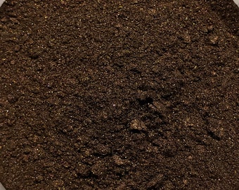May include: A close-up view of a container filled with a dark brown powder. The powder has a slightly shimmery texture.