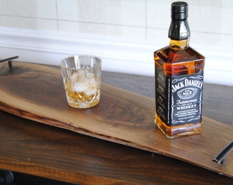 May include: A wooden serving tray with black metal handles, featuring a bottle of Jack Daniel's Tennessee Whiskey and a glass of whiskey with ice.