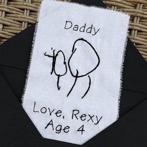 May include: A rectangular white fabric tag with frayed edges featuring black embroidered text that reads Daddy at the top and Love, Rexy Age 4 at the bottom, with a simple black embroidered stick figure drawing of two people in the center.