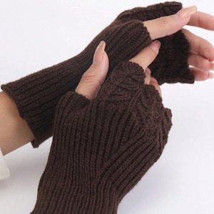 May include: A pair of brown fingerless gloves with a knitted pattern. The gloves are made from a soft, warm material and are ideal for keeping your hands warm in the winter.