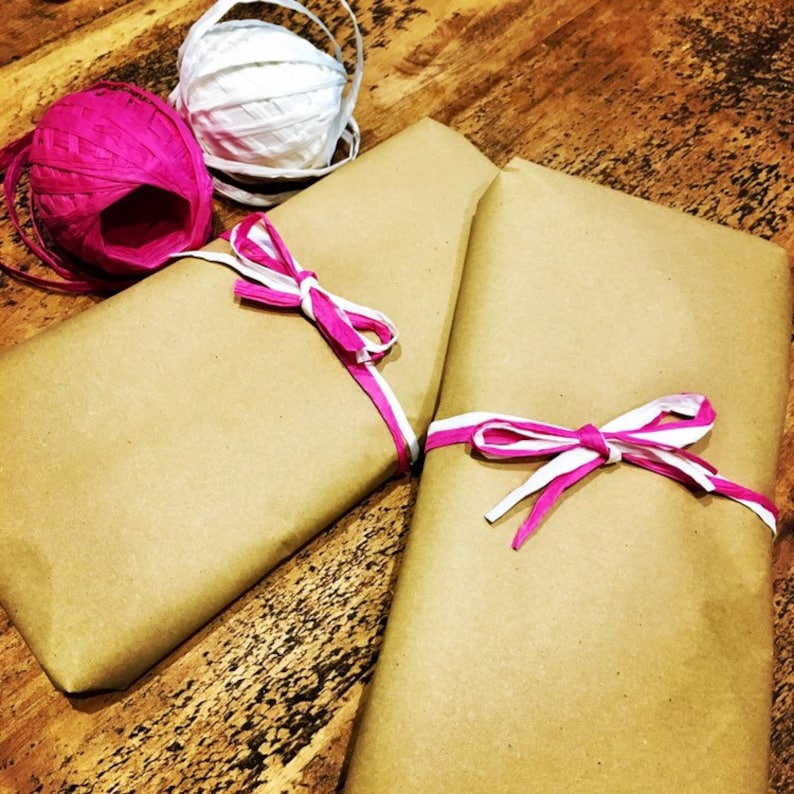 May include: Two brown paper packages tied with pink and white ribbon. The ribbon is tied in a bow on each package.