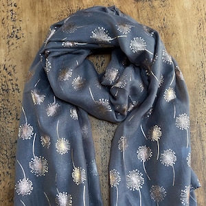 May include: A grey scarf with a gold and silver dandelion print.