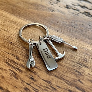 May include: Silver keychain with a ruler charm that says "Dad" and other tool charms, including a wrench, hammer, and screwdriver.