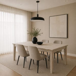 May include: A light-toned wooden dining table with four upholstered chairs featuring dark legs. A black pendant light hangs above the table, which holds a black vase with green foliage and a small black bowl. A framed neutral art piece hangs on the wall.