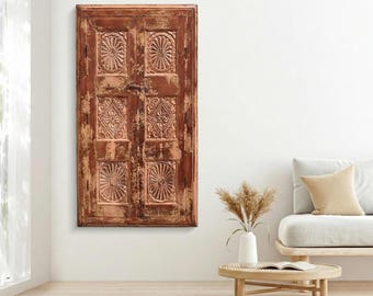May include: A rectangular wooden wall panel featuring a distressed brown finish and six carved square sections. Each section displays intricate embossed patterns, including circular sunburst motifs and diamond-shaped floral designs.