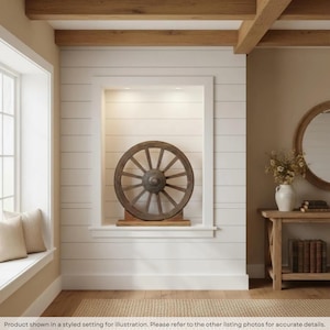 May include: A circular wooden wagon wheel with twelve spokes and a central metal hub, mounted on a rectangular wooden base. The wheel features a dark brown finish and is positioned within a white recessed wall niche.