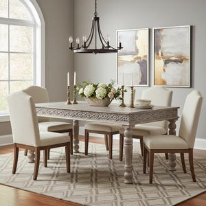 May include: A rectangular wooden dining table with carved apron details and turned legs, surrounded by four upholstered chairs with light beige fabric and brown wooden legs, featuring a centerpiece of white flowers and tall taper candles.