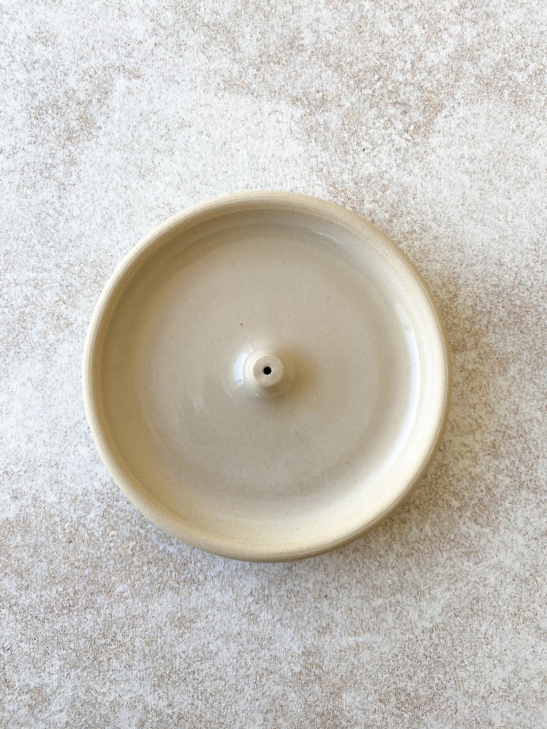Beige handmade round ceramic incense holder.