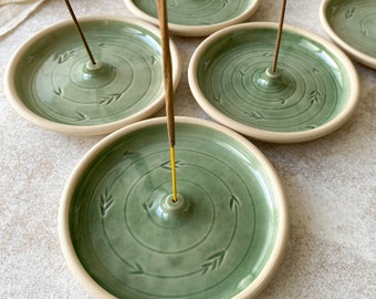 Könnte beinhalten: Set aus vier grünen Keramikknetern mit weißem Rand. Jeder Kneter hat ein kreisförmiges Design mit einem kleinen Loch in der Mitte für Räucherstäbchen.