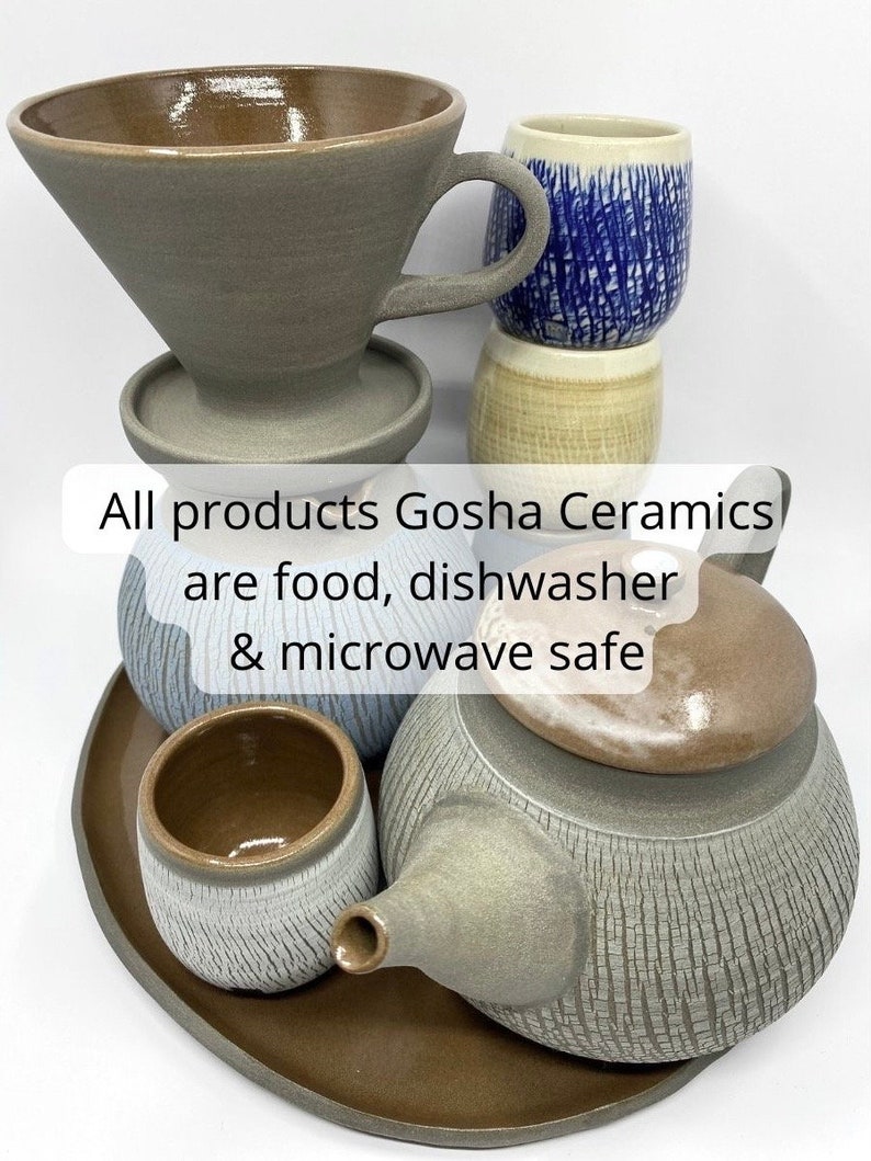May include: A set of gray ceramic kitchenware, including a teapot, a teacup, a coffee filter, and a saucer. The text "All products Gosha Ceramics are food, dishwasher & microwave safe" is visible in the image.