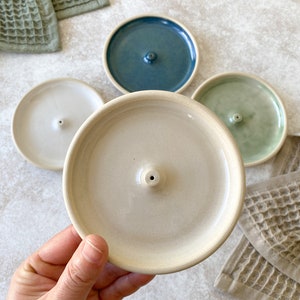 Handmade round ceramic incense burner in green, white, beige and blue.