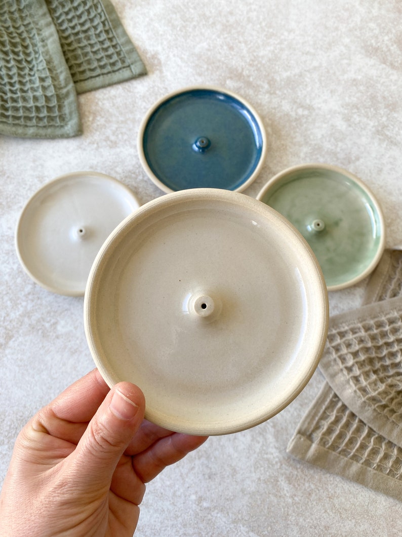 Handmade round ceramic incense burner in green, white, beige and blue.