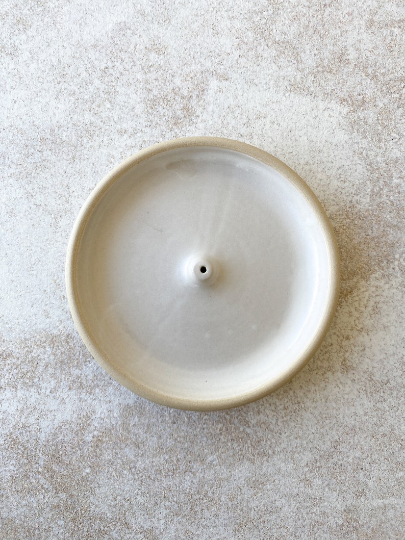 White handmade round ceramic incense holder.