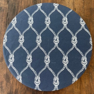 May include: A round blue placemat with a white rope pattern. The pattern is a repeating design of knots and ropes.