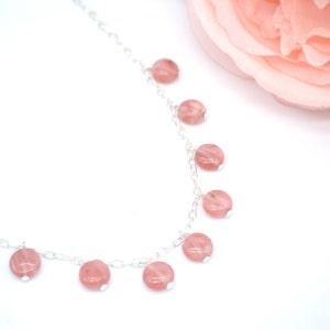 May include: A delicate silver chain necklace with pink gemstone beads. The beads are round and have a subtle shimmer.