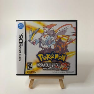 May include: A Nintendo DS game case for "Pokémon White Version 2." The case features a white and blue legendary Pokémon with the game title in yellow and red. The ESRB rating is visible.