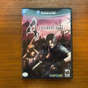 May include: A Nintendo GameCube video game case for Resident Evil 4. The cover art features a man with short brown hair, surrounded by zombies. The game title is in white, with a stylized logo. The Capcom logo is visible.