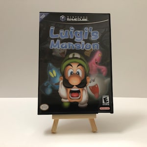 May include: A Nintendo GameCube game case with a black background and a green, white, and red image of Luigi from the game "Luigi's Mansion". The game is rated "E" for Everyone by the ESRB.