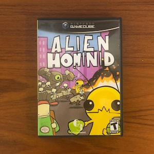 May include: A video game case for the Nintendo GameCube. The case is black with a purple, yellow, and orange design. The game title is "Alien Hominid".