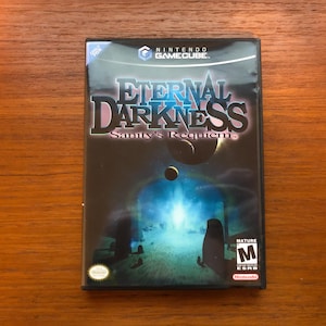 May include: A black Nintendo GameCube game case featuring a blue and white image of a dark, mysterious world. The game title is "Eternal Darkness: Sanity's Requiem".