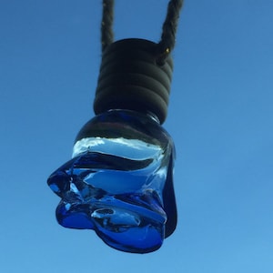 Puede incluir: Un ambientador de coche de vidrio azul con forma de flor que cuelga de una cuerda.