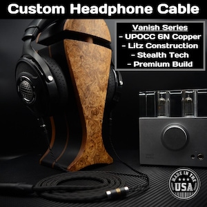 May include: A custom headphone cable with a black braided design, paired with a wooden headphone stand and a silver amplifier. The image includes text that reads "Vanish Series - UPOCC 6N Copper - Litz Construction - Stealth Tech - Premium Build."