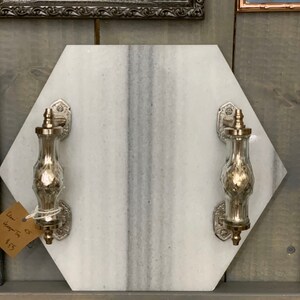 May include: Hexagon shaped marble serving tray with two silver and glass handles. The tray is white with gray veining. The price tag reads "Large $35 Hanging Trim $4.55".
