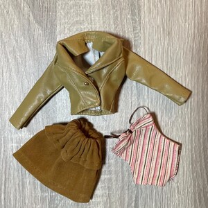 “1960s–70s 1/6 doll outfit with faux leather jacket, suede skirt, and striped top fits Sindy and Blythe.” shown on 1980's Sindy Doll, blonde hair blue eyes. yellow lipstick