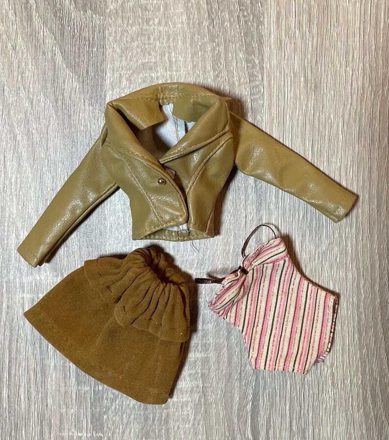 “1960s–70s 1/6 doll outfit with faux leather jacket, suede skirt, and striped top fits Sindy and Blythe.” shown on 1980's Sindy Doll, blonde hair blue eyes. yellow lipstick