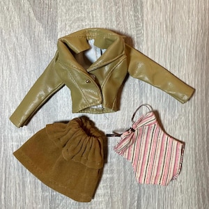 “1960s–70s 1/6 doll outfit with faux leather jacket, suede skirt, and striped top fits Sindy and Blythe.” shown on 1980's Sindy Doll, blonde hair blue eyes. yellow lipstick
