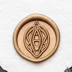 May include: A gold wax seal with a stylized design on a white heart-shaped paper background.