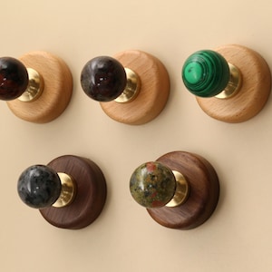 May include: Five decorative wooden knobs with brass hardware and stone or marble spheres. The knobs feature a variety of colors, including brown, green, and gray. These knobs are suitable for cabinets, drawers, or other furniture.