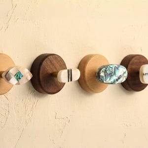 Peut inclure: Quatre patères murales décoratives en bois avec des boutons uniques, colorés et à motifs. Les boutons présentent divers motifs, dont de l'ormeau et des motifs incrustés, montés sur des bases rondes en bois.