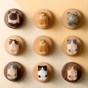 May include: Nine wooden cat sculptures mounted on round wooden plaques. The cats are carved in a geometric style, with various colours and patterns, including brown, orange, grey, and black. The plaques are arranged in a grid pattern against a light yellow background.